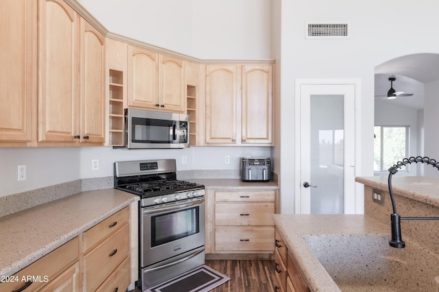 kitchen featuring visible vents, light stone counters, stainless steel appliances, and light brown cabinetry