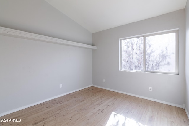 unfurnished room with light wood-style floors, lofted ceiling, and baseboards