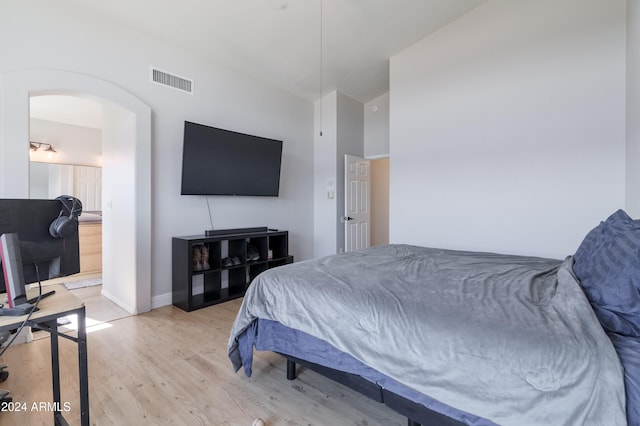 bedroom with arched walkways, baseboards, visible vents, and light wood-style floors