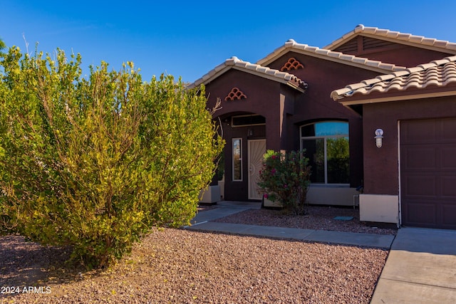 view of front of home with a garage, a tile roof, and stucco siding