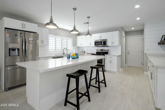 kitchen featuring white cabinets, appliances with stainless steel finishes, decorative backsplash, and light countertops