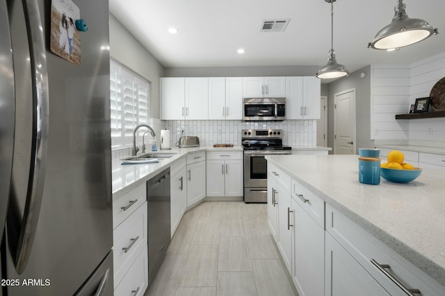 kitchen with visible vents, decorative backsplash, appliances with stainless steel finishes, white cabinets, and a sink