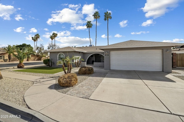 ranch-style house featuring concrete driveway, a front yard, an attached garage, and stucco siding