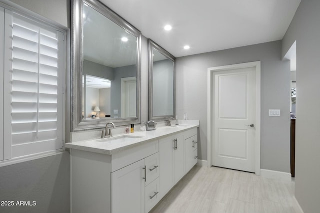 bathroom with recessed lighting, a sink, baseboards, and double vanity