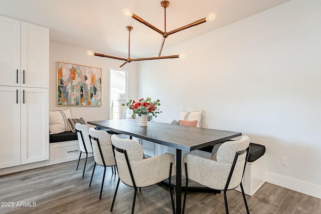 dining space with a notable chandelier, wood finished floors, and baseboards