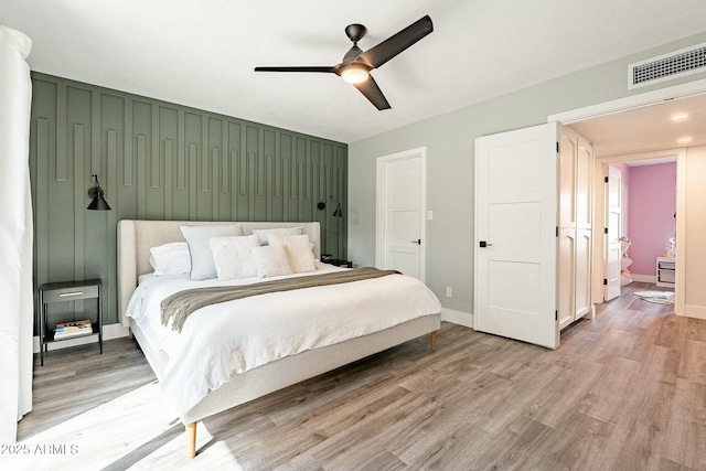 bedroom with a ceiling fan, visible vents, light wood-style flooring, and baseboards