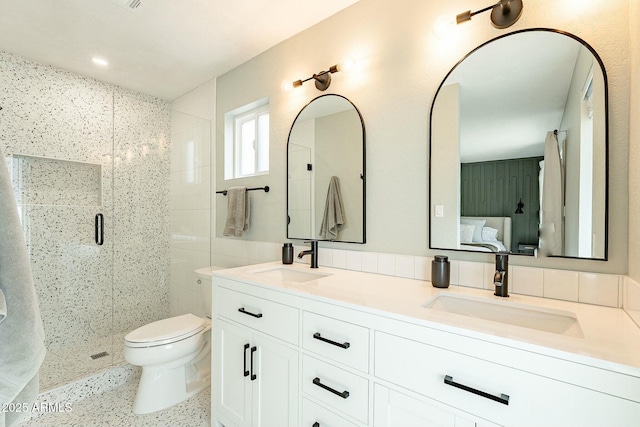 bathroom featuring double vanity, a sink, toilet, and a shower stall