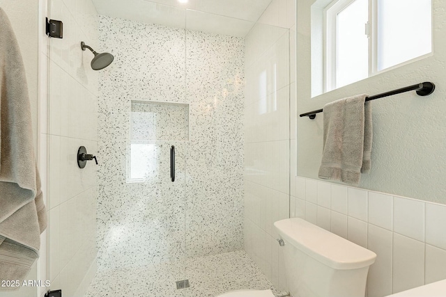 full bath with toilet, a stall shower, a healthy amount of sunlight, and tile walls