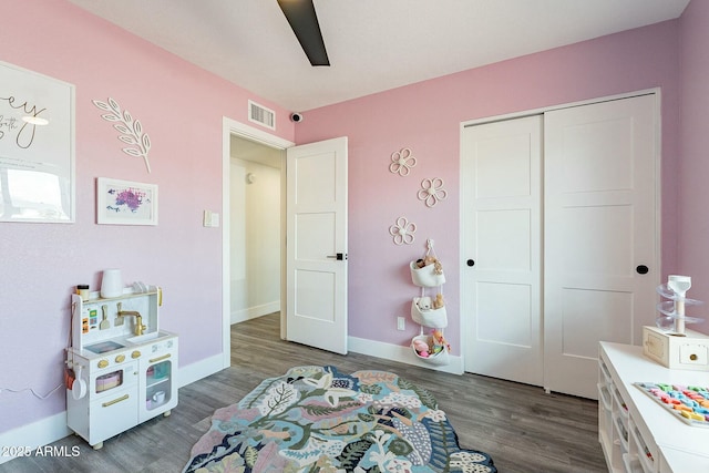 bedroom with a closet, wood finished floors, visible vents, and baseboards