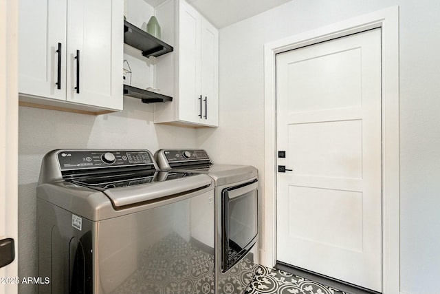 clothes washing area featuring cabinet space, tile patterned floors, and washing machine and clothes dryer