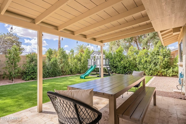 view of patio with outdoor dining area, a playground, and a fenced backyard