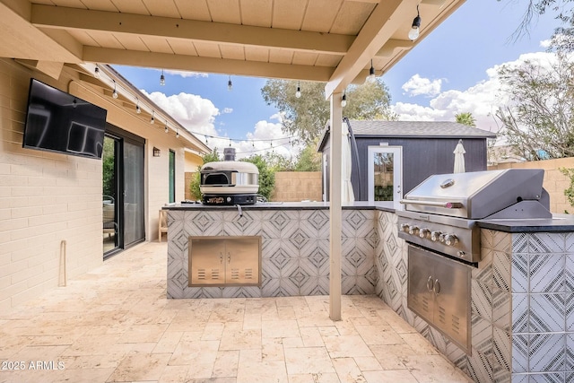 view of patio featuring an outdoor kitchen, fence, grilling area, and an outbuilding