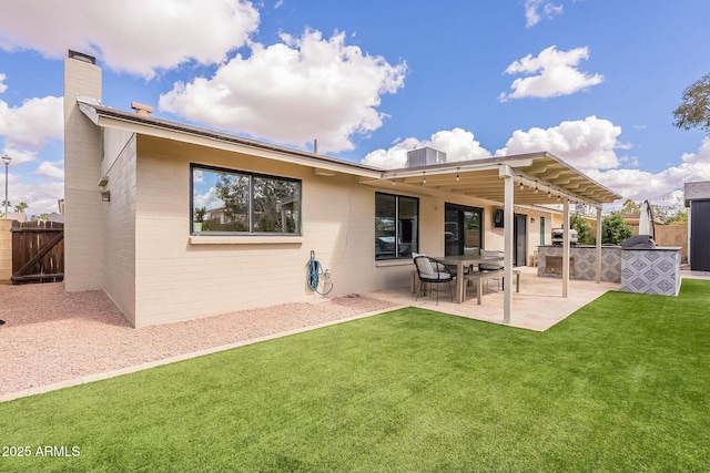 rear view of property featuring a patio, concrete block siding, fence, a lawn, and a chimney