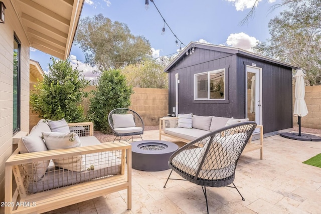 view of patio / terrace with fence, an outdoor structure, and an outdoor living space with a fire pit