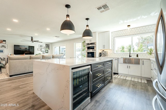 kitchen featuring beverage cooler, visible vents, stainless steel appliances, white cabinetry, and a sink