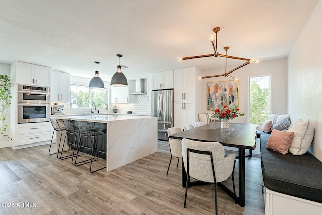 kitchen featuring stainless steel appliances, wall chimney exhaust hood, a wealth of natural light, and a center island