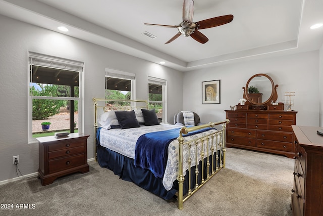 bedroom with ceiling fan, a raised ceiling, and light carpet