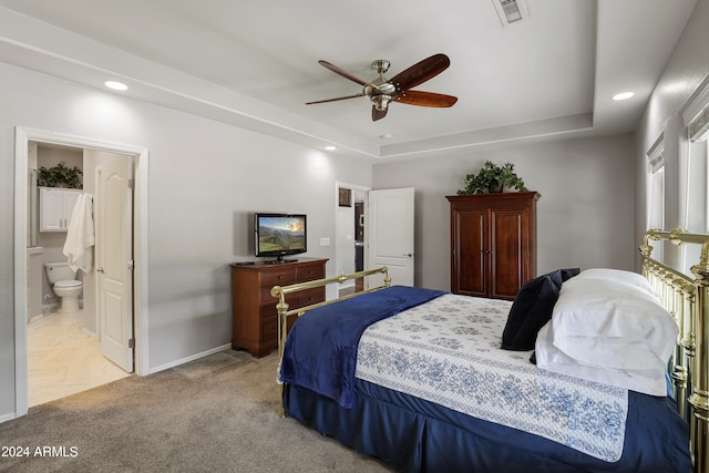 bedroom with connected bathroom, light parquet flooring, ceiling fan, and a raised ceiling