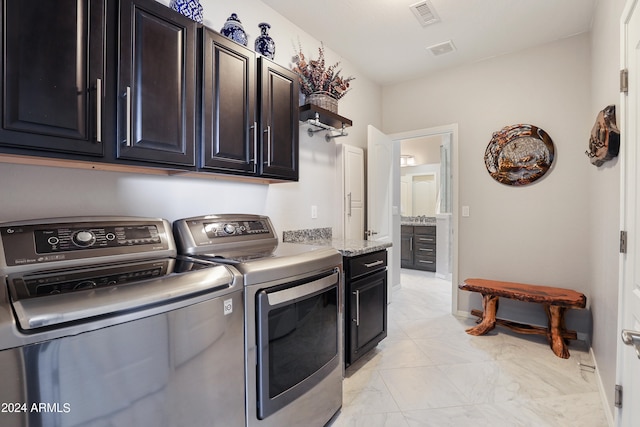 laundry area featuring washer and dryer, light tile patterned flooring, and cabinets