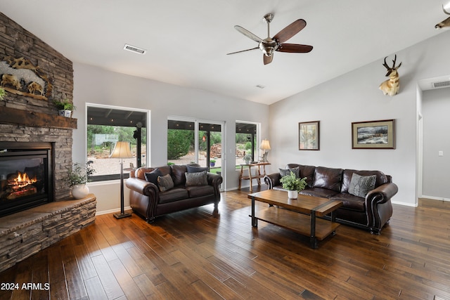 living room with a stone fireplace, dark wood-type flooring, vaulted ceiling, and a wealth of natural light