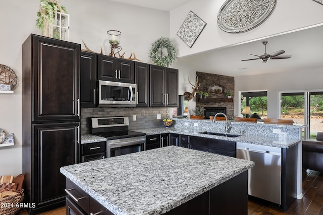 kitchen with decorative backsplash, dark wood-type flooring, a fireplace, stainless steel appliances, and sink