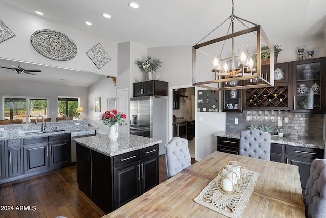 kitchen with tasteful backsplash, pendant lighting, lofted ceiling, sink, and dark wood-type flooring