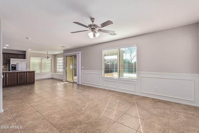 unfurnished room with a healthy amount of sunlight, ceiling fan with notable chandelier, and light tile patterned floors