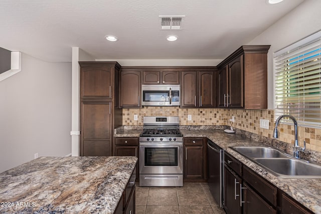 kitchen featuring dark brown cabinets, stainless steel appliances, sink, and backsplash