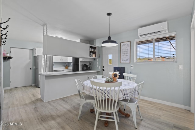 dining space featuring light wood finished floors, baseboards, and a wall mounted AC