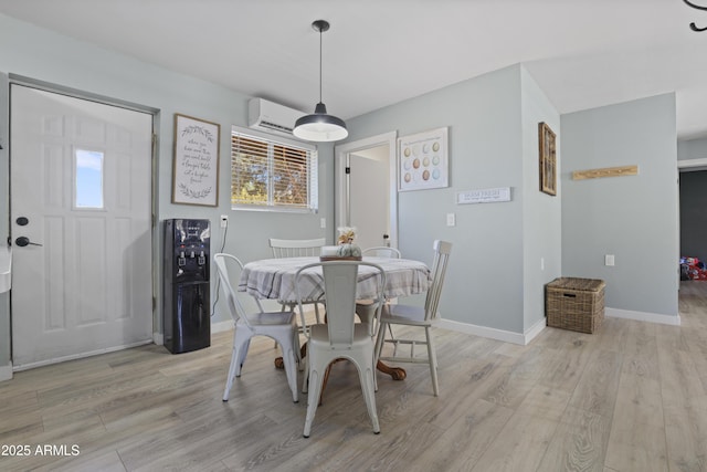 dining area with light wood-type flooring, baseboards, and a wall mounted air conditioner