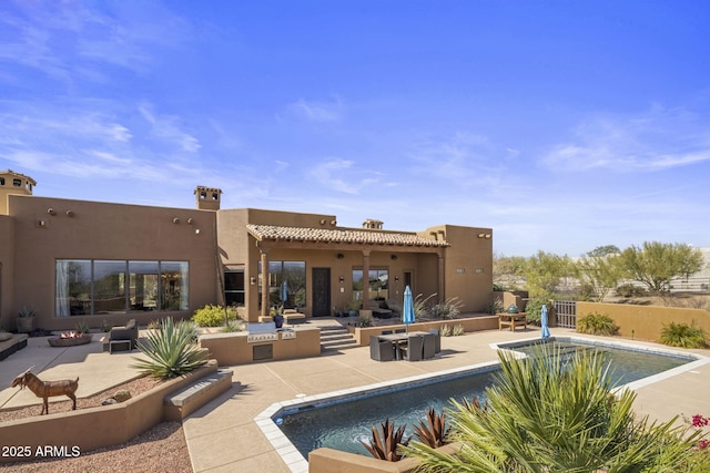 rear view of house featuring a patio, a fenced in pool, fence, an outdoor fire pit, and stucco siding