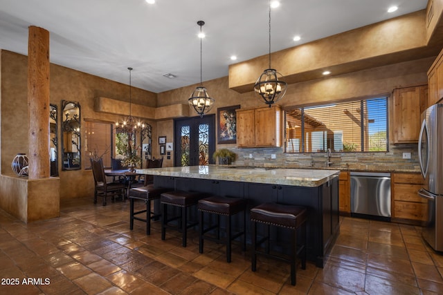 kitchen featuring brown cabinetry, an inviting chandelier, decorative backsplash, appliances with stainless steel finishes, and a center island