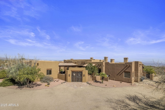 adobe home with stucco siding and a gate