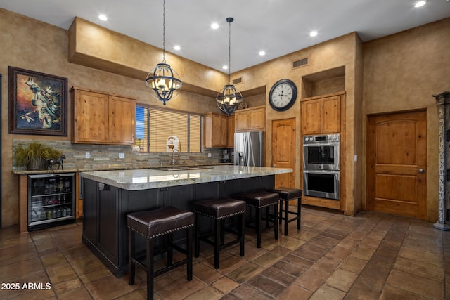 kitchen with visible vents, a kitchen island, stainless steel appliances, decorative backsplash, and wine cooler