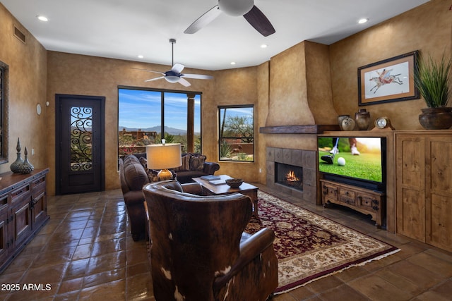 living area featuring a tiled fireplace, recessed lighting, visible vents, and ceiling fan