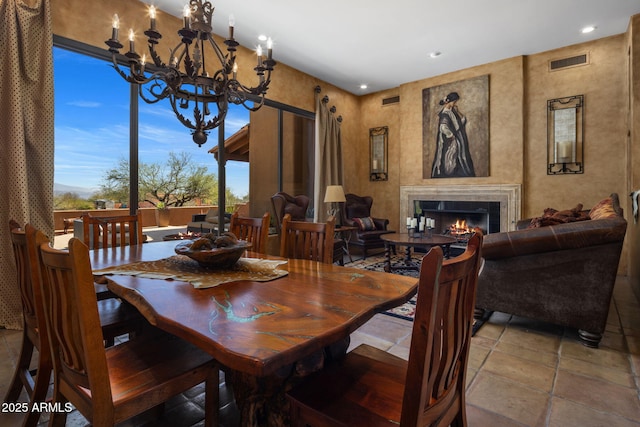 dining room with visible vents, recessed lighting, a warm lit fireplace, and an inviting chandelier