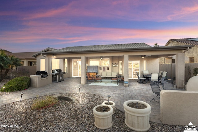 back house at dusk featuring ceiling fan, area for grilling, outdoor lounge area, and a patio