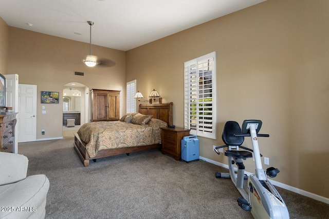 carpeted bedroom with connected bathroom and a high ceiling