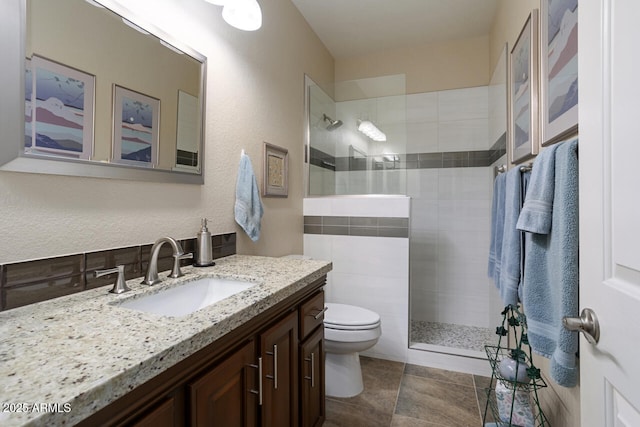 bathroom featuring a tile shower, vanity, and toilet