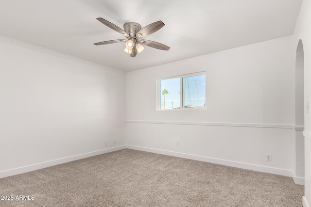 unfurnished room featuring ceiling fan, baseboards, arched walkways, and carpet flooring