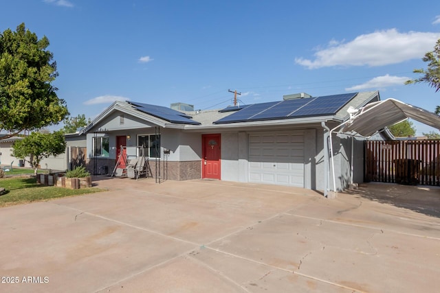 single story home featuring stucco siding, concrete driveway, an attached garage, roof mounted solar panels, and fence