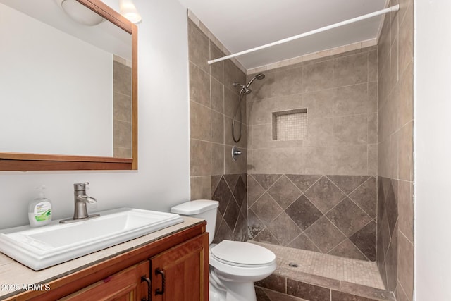 bathroom featuring tiled shower, vanity, and toilet