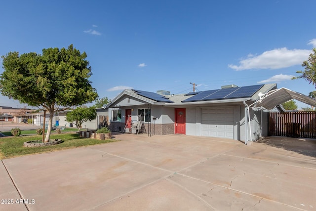 ranch-style house with a garage, solar panels, fence, concrete driveway, and stucco siding