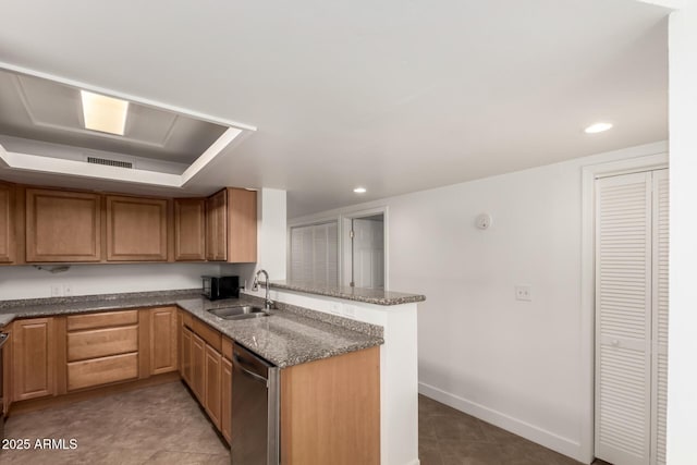 kitchen featuring a peninsula, a sink, baseboards, stainless steel dishwasher, and dark stone counters