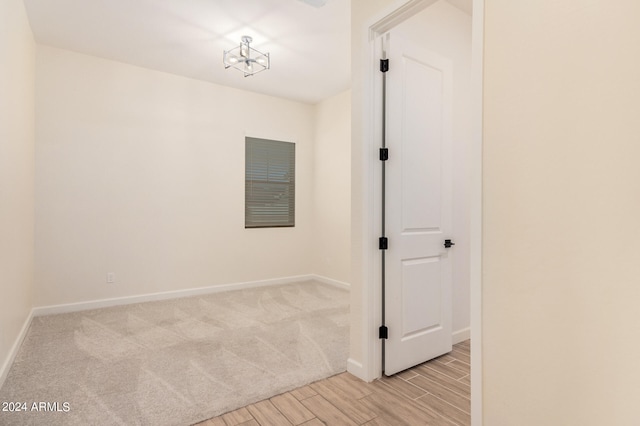 spare room featuring a chandelier and light colored carpet