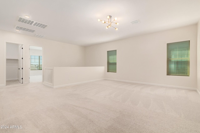 empty room with an inviting chandelier and light colored carpet