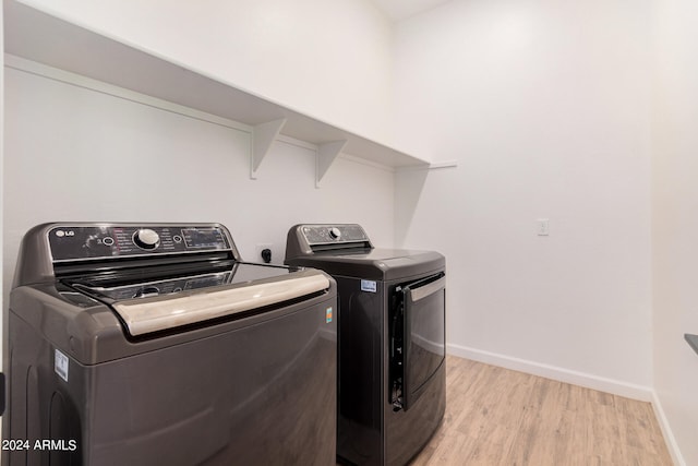 laundry room with light wood-type flooring and washing machine and clothes dryer