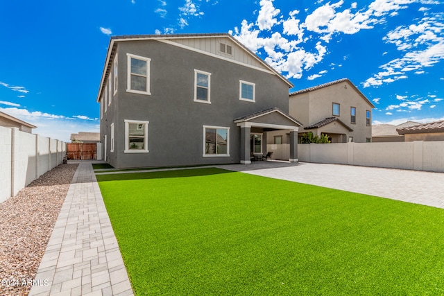 back of house with a lawn and a patio area