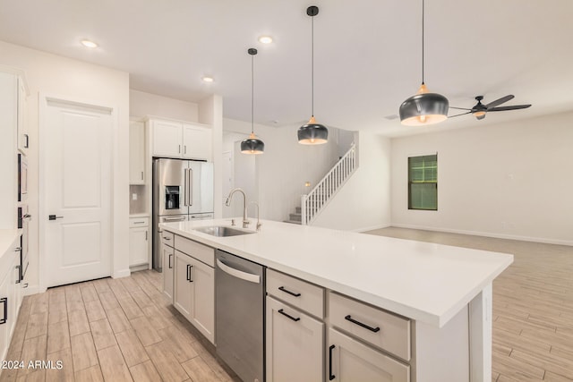 kitchen with appliances with stainless steel finishes, a kitchen island with sink, sink, white cabinetry, and ceiling fan