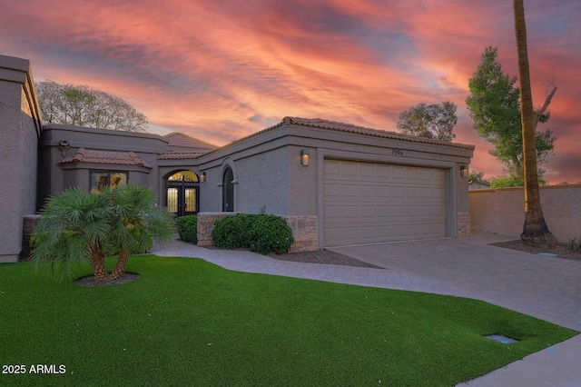 7596 N Via De La Siesta, Scottsdale, AZ 85258 - mediterranean / spanish-style house with a tiled roof, an attached garage, concrete driveway, stone siding, and a front lawn